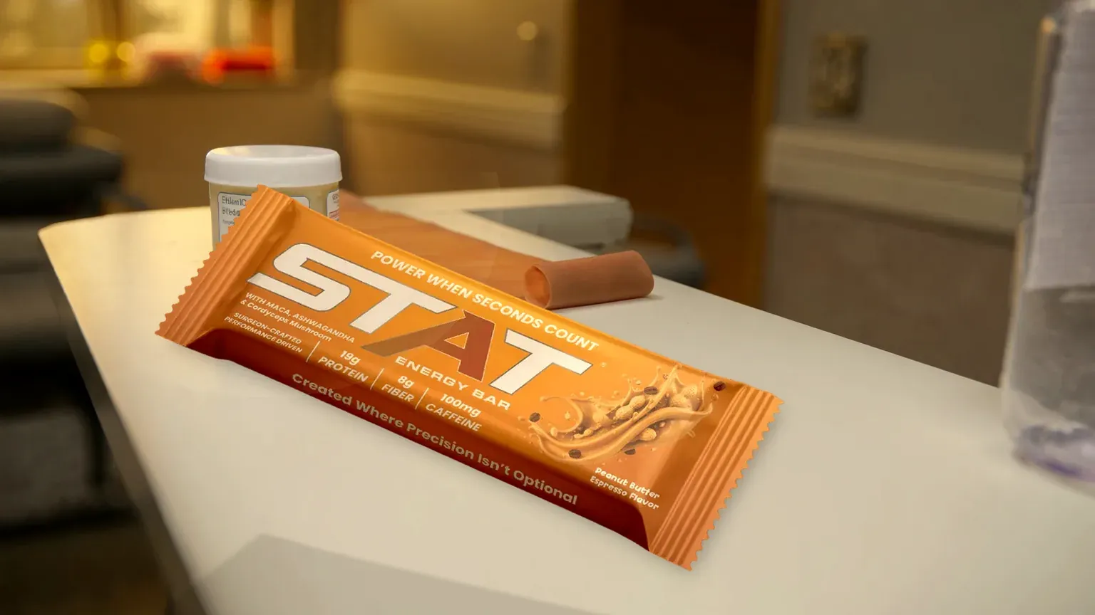 Real STAT Peanut Butter Espresso Energy Bar on a cream outpatient occupational therapy clinic desk between sessions, with a therapy putty jar, folded terracotta resistance band, and water bottle; warm copper key light and soft clinic blur beyond.